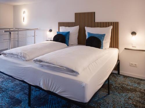 ein großes Bett mit weißen Laken und blauen Kissen in der Unterkunft Das Hartmanns in Pegnitz