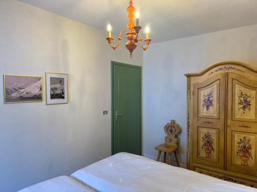 a bedroom with a bed with a green door and a chandelier at Passo Carezza Club Apartment in Carezza al Lago