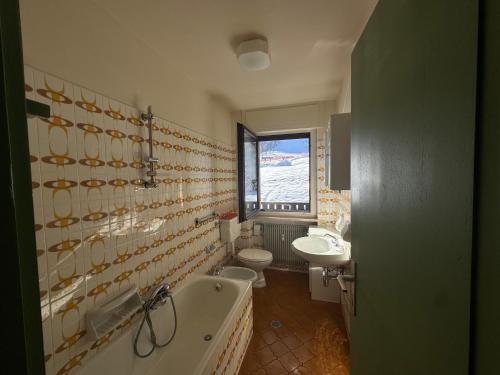 a bathroom with a tub and a toilet and a sink at Passo Carezza Club Apartment in Carezza al Lago