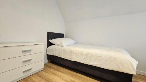 a small bedroom with a bed and a dresser at Fieldorfa House in Ostrołęka