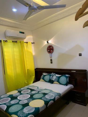 a bed in a room with yellow and green curtains at Hôtel Okpèyèmi in Porto-Novo