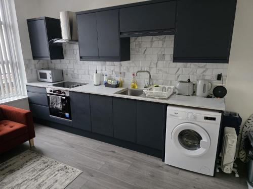 a kitchen with a sink and a washing machine at Modern 2 Bed Apartment, Desborough, Kettering, Sleeps 5, Free Parking, WIFI, Ideal for Contractors, Professionals, Families and Relocations in Kettering