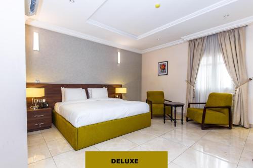 a hotel room with a bed and a desk and chairs at Joygate Hotels & Suites in Lagos