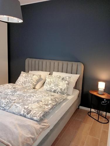 a bed in a bedroom with a blue wall at Apartament 42 in Sosnowiec