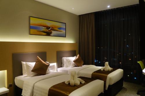 a hotel room with two beds with white towels at Greens Hotel & Suites in Bintulu