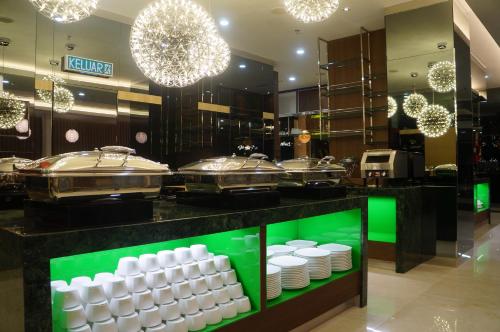 a restaurant counter with white plates and chandeliers at Greens Hotel & Suites in Bintulu