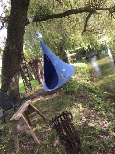 a blue tent and a chair next to a tree at Au Paddock du Bec in Le Bec-Hellouin