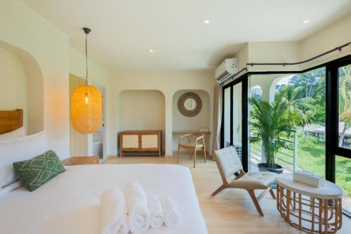 a bedroom with a white bed and a large window at ELYSIUM Villa Khao Lak in Khao Lak