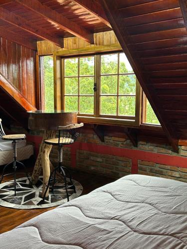 a bedroom with a bed and a piano and windows at Chale do Morro in Marques de Sousa
