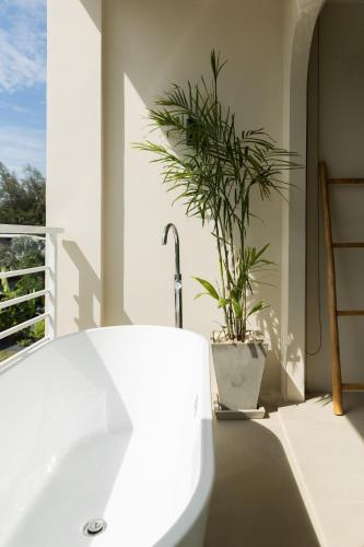 a bathroom with a white tub and a potted plant at ELYSIUM Villa Khao Lak in Khao Lak
