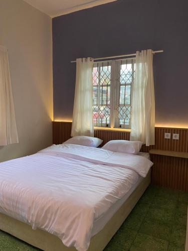 a bedroom with a bed with white sheets and a window at Rasa Jogja Homestay in Yogyakarta