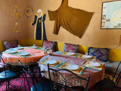 two tables in a restaurant with a mannequin on the wall at Auberge el oasis mharech in Foum Mharech