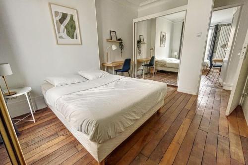 a bedroom with a large bed and a dining room at Room in elegant and charming 3-bedroom apartment near Bois de Vincennes in Paris