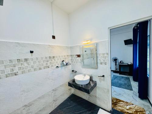 a white bathroom with a sink and a mirror at Mist Cave Ella in Etimale