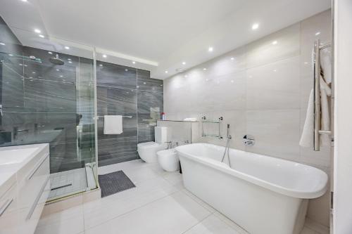 a bathroom with a tub and a toilet and a sink at Luxury Camps Bay Getaway in Cape Town