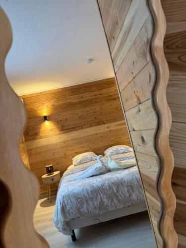 a bedroom with a bed with a wooden wall at Le ptit Chalet du bonheur in Entre-Deux