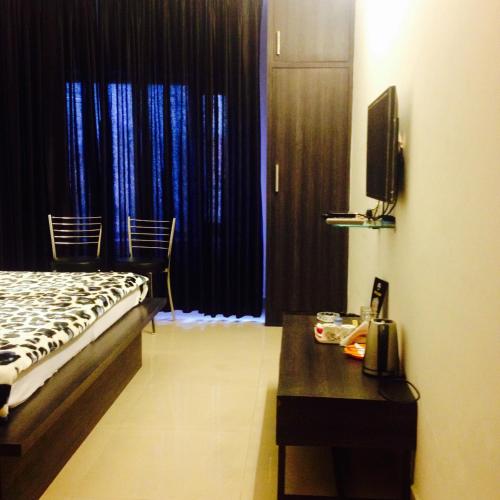 Un dormitorio con una cama, una mesa y un televisor. en Hotel Shree, en Hisār