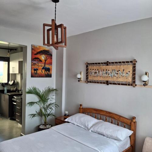a bedroom with a bed and a chandelier at Spacious Studio Apartment with Swimming pool in Nairobi