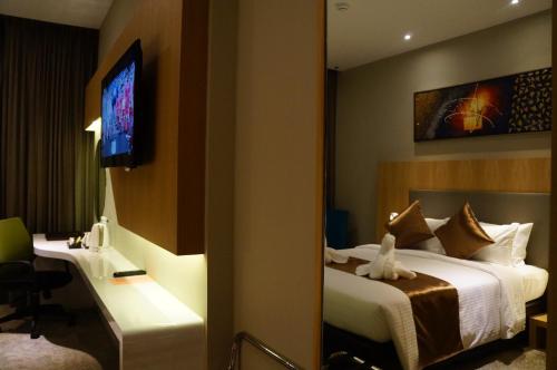a hotel room with a bed and a desk and a television at Greens Hotel & Suites in Bintulu