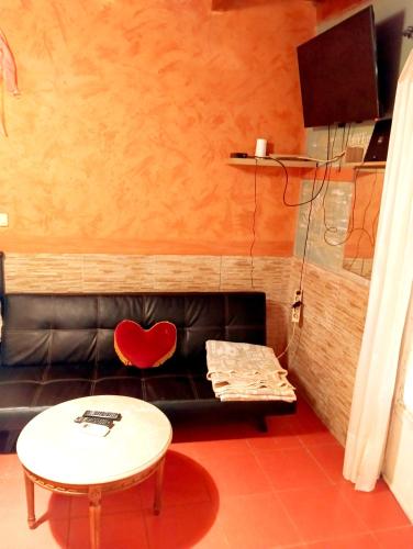 a living room with a black leather couch and a table at Το Μικρό Σπίτι στη Φάρμα! in Acharnes