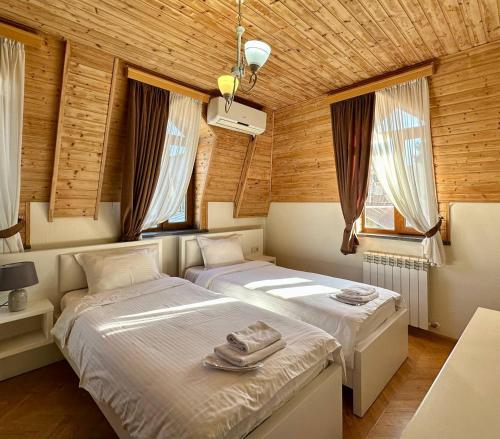 two beds in a room with wooden walls and windows at Four brother in Tbilisi City