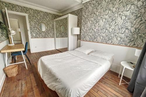 a bedroom with a bed and a wall with wallpaper at Room in elegant 3-bedroom apartment near Bois de Vincennes in Paris