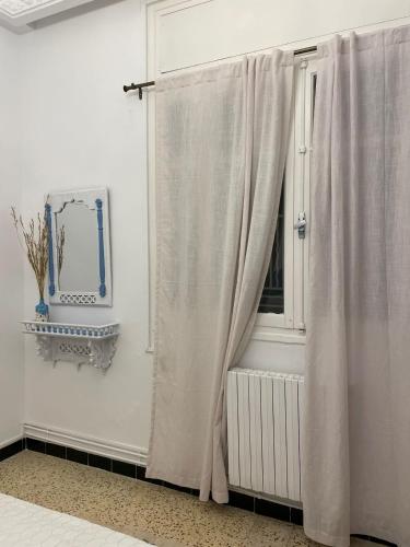 a room with a window with a curtain and a mirror at Nomads Hostel Sousse in Sousse
