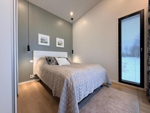 a bedroom with a bed and a large window at Willa Koivuranta Kajaani in Pikkuhannus