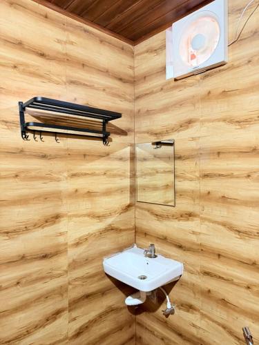 a bathroom with a white sink and wooden walls at VIVIPRA Habitat, Coorg in Madikeri