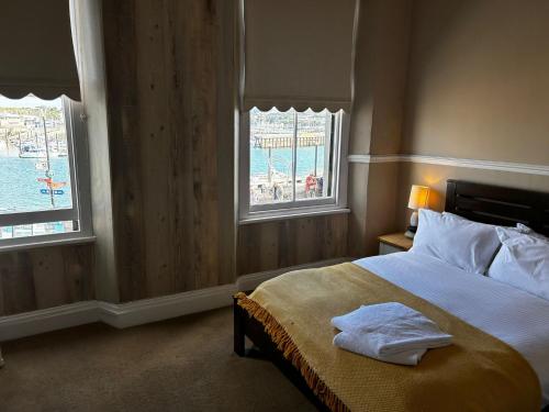a bedroom with a bed with two windows at Admiral MacBride Bed & Breakfast in Plymouth