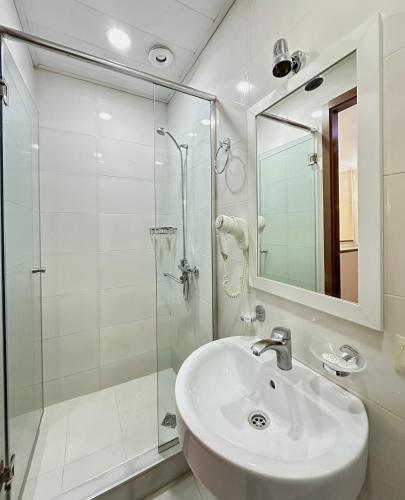 a white bathroom with a sink and a shower at Four brother in Tbilisi City