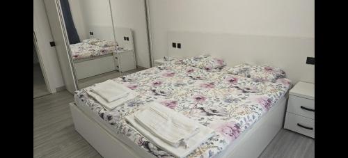 a bedroom with a bed with a floral comforter and a mirror at Ultracentral Piata in Caracal