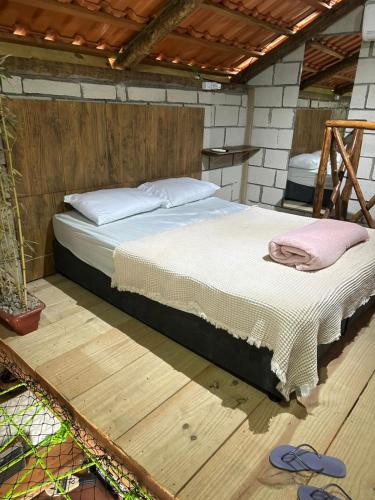 a bed in a room with a wooden floor at Chalé Orquídea com vista para as montanhas in Palmeiras