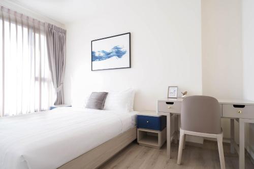a white bedroom with a bed and a desk and a chair at The Hampton Suites Bangna in Bangna