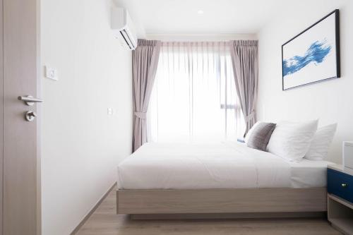 a bedroom with a white bed with a window at The Hampton Suites Bangna in Bangna