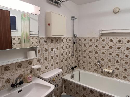 a bathroom with a sink and a tub and a toilet at Chesa Chatrigna App 6 - Celerina in Celerina