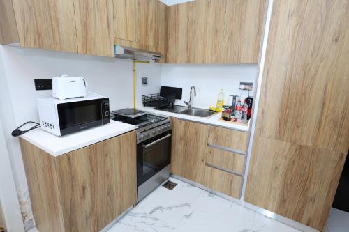 a small kitchen with a microwave and a sink at 1 Bed Junior near Cleveland and Galleria Mall by Central Stay in Abu Dhabi