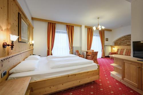 una camera da letto con un grande letto e una televisione di Hotel Ronce a Ortisei