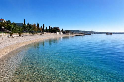 a beach with blue water and trees on it at Villa Trogir in Trogir