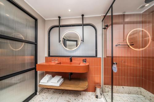 a bathroom with a sink and a mirror at Courtyard Hotel Gqeberha in Port Elizabeth