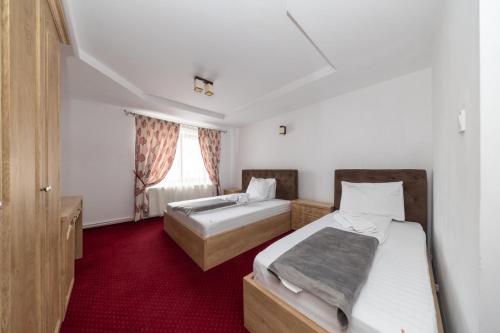 two beds in a room with red carpet at Pensiunea Rosenau in Râşnov