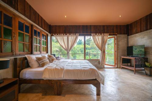 a bedroom with a bed and a large window at Cozy Home Saluang in Ban Lua Ka