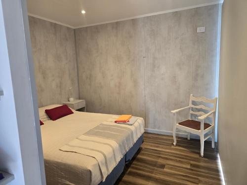 a small bedroom with a bed and a chair at Altos Dique Potrerillos in Potrerillos