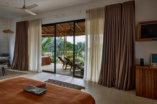 a bedroom with a bed and a large sliding glass door at Yokan Lodge in Palmarin