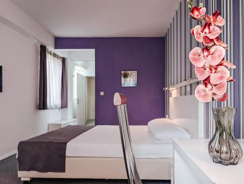 a bedroom with a bed and a vase of flowers at Violet Stay in Skopje