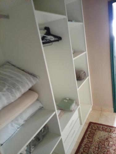 a white closet with white shelves and pillows at Quarto Suite & Cozinha in Piraju