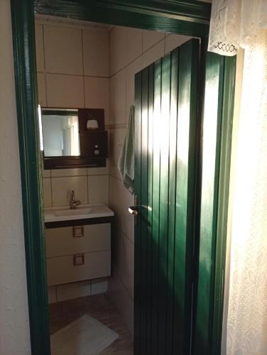 a bathroom with a green door and a sink at Quarto Suite & Cozinha in Piraju