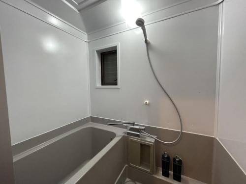 a bathroom with a bath tub with a light on the wall at Guest house TOMORI - Vacation STAY 11064v in Shingū