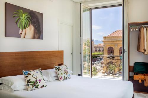 a bedroom with a white bed and a large window at Palazzo Sovrana Serviced Luxury Apartments in Palermo