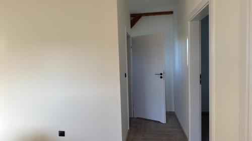 a hallway with white walls and a white door at Ranczo pod dębami in Wola Smolana
